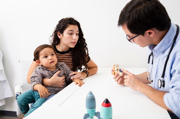 Médico de visão lateral explicando a uma mãe