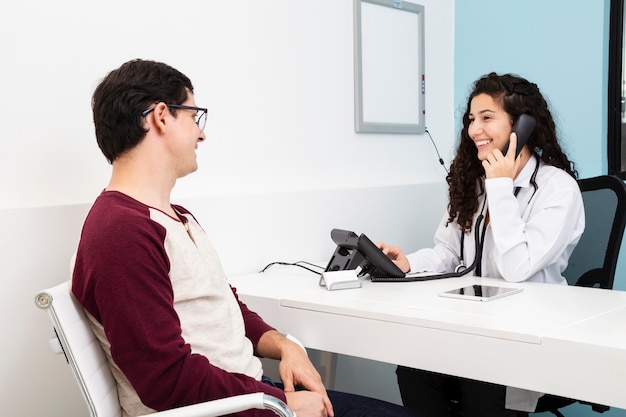 Médico de visão lateral falando no telefone