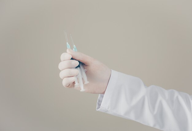Médico de vista lateral com luvas com seringas na mão. horizontal