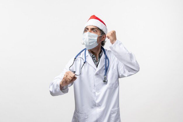 Médico do sexo masculino com máscara sobre um vírus covid pandêmico de férias de parede branca