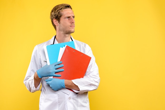 Médico do sexo masculino de vista frontal segurando análises sobre fundo amarelo saúde médico vírus humano