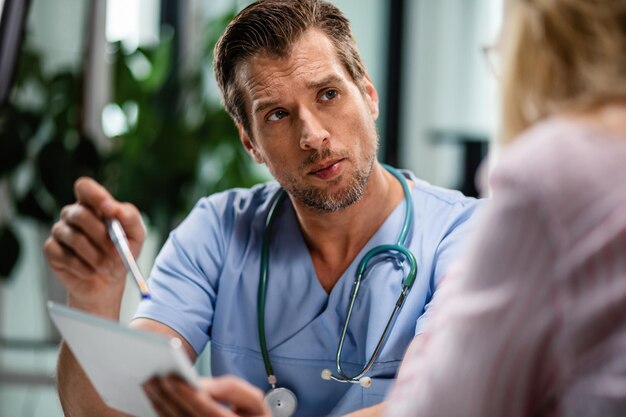 Foto grátis médico do sexo masculino se comunicando com paciente do sexo feminino ao usar o touchpad e passando por relatórios médicos eletrônicos