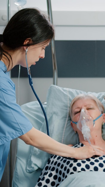 Foto grátis médico e enfermeiro usando máscara de tubo de oxigênio para paciente idoso com respiração pesada e problemas respiratórios em enfermaria de hospital. especialistas médicos que tratam de mulheres doentes com hiperventilação na cama