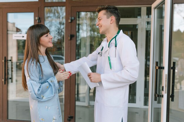 Médico e paciente alegre na entrada da clínica