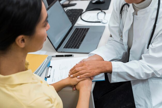 Médico e paciente de mãos dadas após más notícias