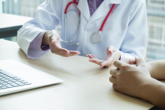 Médico e paciente estão discutindo algo, apenas as mãos na mesa