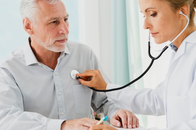 Médico escrevendo notas enquanto ausculta