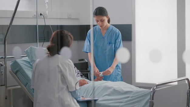 Médico especialista em uniforme médico verificando homem doente escrevendo experiência em doenças