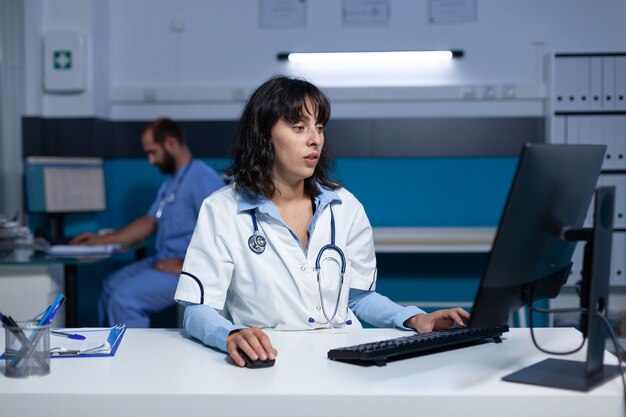 Médico especialista usando computador e teclado à noite