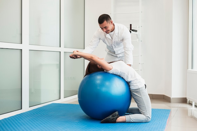 Médico, esticar o paciente na bola de exercício