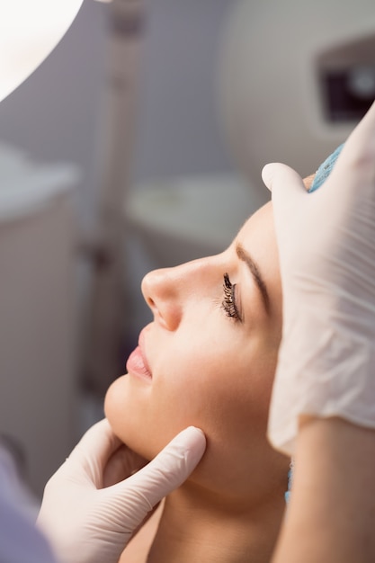 Médico examinando o rosto da mulher para tratamento cosmético
