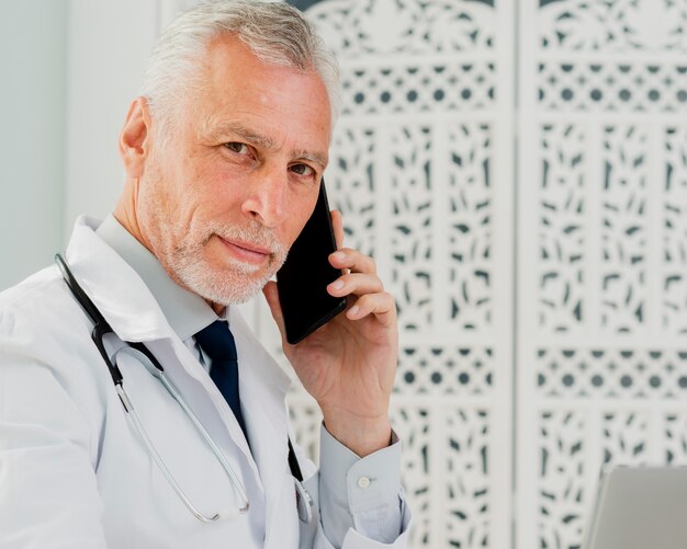 Médico falando ao telefone, olhando para a câmera