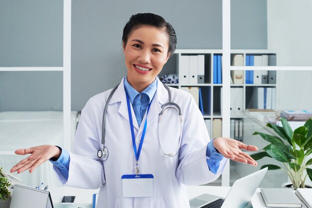 Médico feminino asiático sorridente posando no escritório