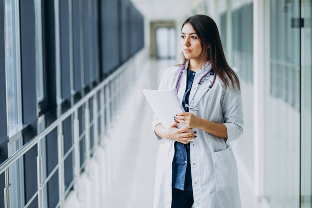 Médico feminino atraente em pé com documentos no hospital