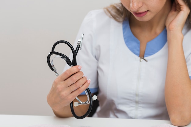 Médico feminino close-up mãos segurando um estetoscópio