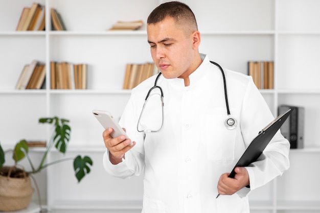 Médico homem segurando um telefone e uma prancheta