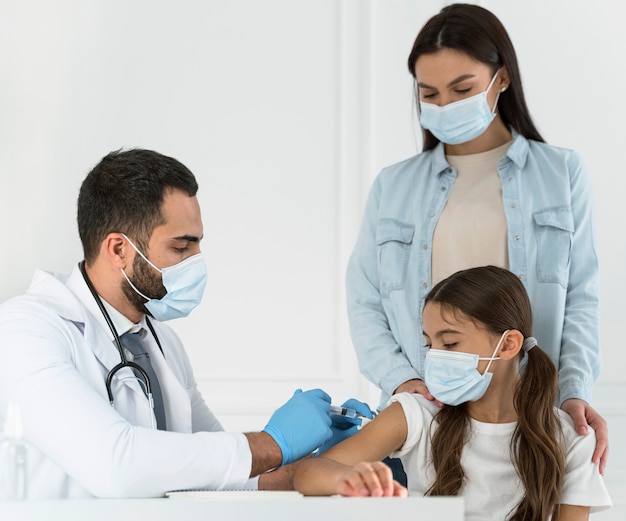 Médico homem vacinando uma menina