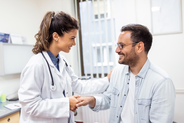 Médico jovem ou GP em uniforme médico branco consulta paciente do sexo masculino em hospital privado Terapeuta feminino fala conversa com cliente homem em consulta na clínica