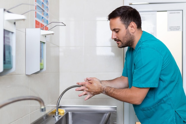 Médico lavando as mãos com sabão cirurgião masculino está se preparando para cirurgia ele está de uniforme na sala de cirurgia