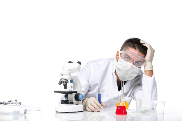 Médico masculino de vista frontal com terno branco e máscara devido a ambicioso trabalhar com soluções no espaço em branco