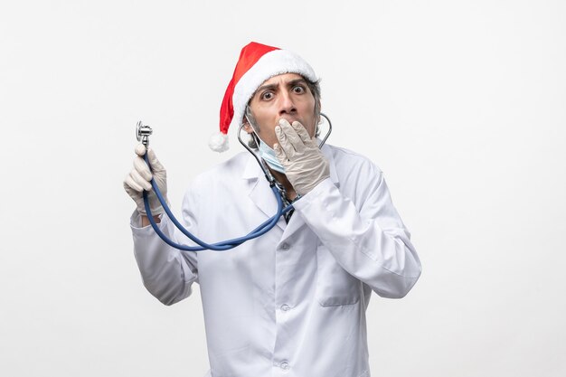 Médico masculino segurando um estetoscópio sobre o vírus da parede branca e emoções
