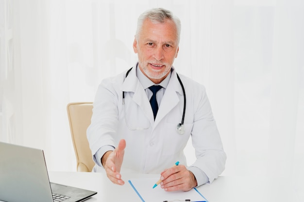 Médico na mesa segurando a mão dele