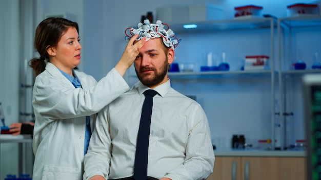 Médico neurologista analisando o cérebro do homem e o sistema nervoso usando fone de ouvido de varredura de ondas cerebrais. Pesquisador usando alta tecnologia, desenvolvendo inovação neurológica, monitorando efeitos colaterais na tela do monitor