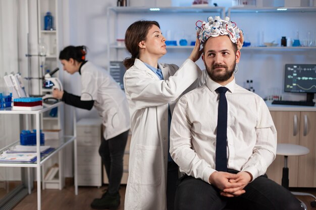 Médico neurologista analisando o cérebro do homem e o sistema nervoso usando fone de ouvido de varredura de ondas cerebrais. Pesquisador usando alta tecnologia, desenvolvendo inovação neurológica, monitorando efeitos colaterais na tela do monitor