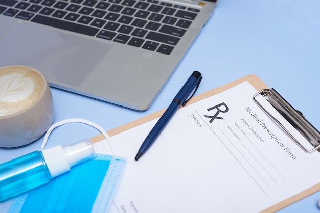 Médico no local de trabalho. Estetoscópio médico, laptop, área de transferência em branco e caneta na superfície azul clara. coronavírus (COVID-19. estetoscópio, óculos e máscara facial. Vista superior, configuração plana, copie o espaço.