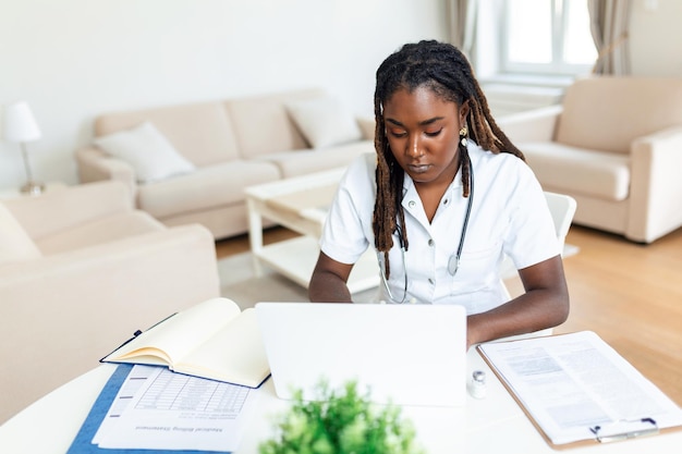 Médico omã africano falando on-line com o paciente fazendo videochamada olhando para a câmera jovem mulher vestindo uniforme branco com estetoscópio falando consultoria e conceito de terapia