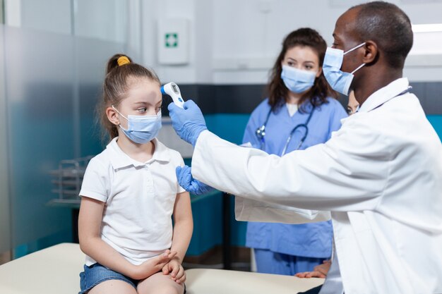 Médico pediatra afro-americano com máscara facial contra coronavírus