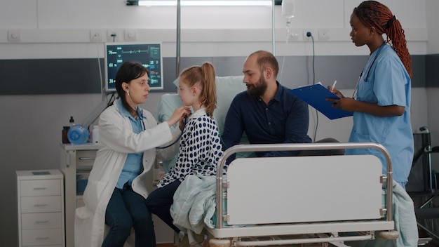 Médico pediatra, consultando os pulmões, ouvindo os batimentos cardíacos, usando um estetoscópio médico