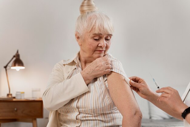 Médico preparando a vacina para uma mulher idosa