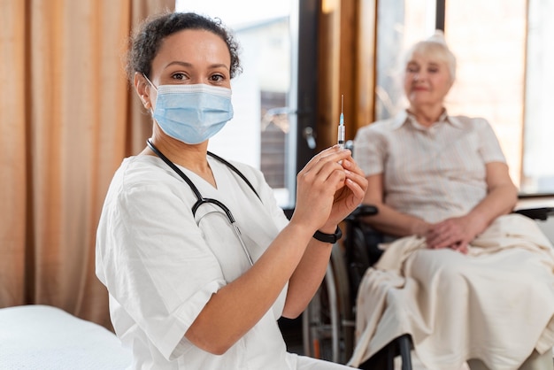 Médico preparando a vacina para uma mulher idosa