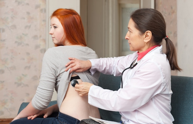 Médico que examina paciente adolescente com estetoscópio