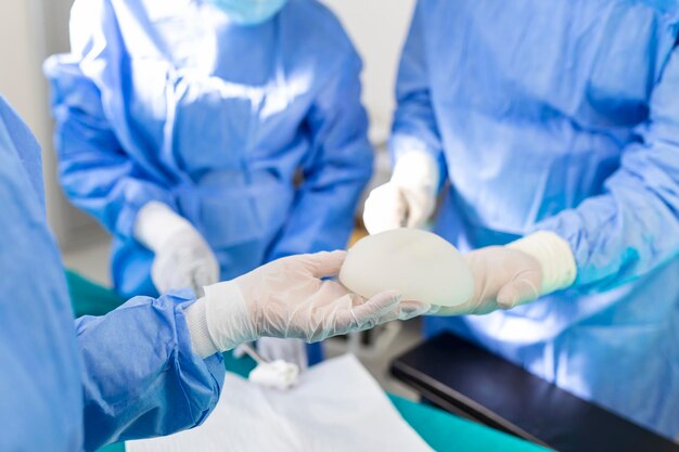 Médico segurando implante de silicone médico Surgente segura implante de silicone e instala no busto de mulher closeup Intervenção cirúrgica conceito de negócio de aumento de mama