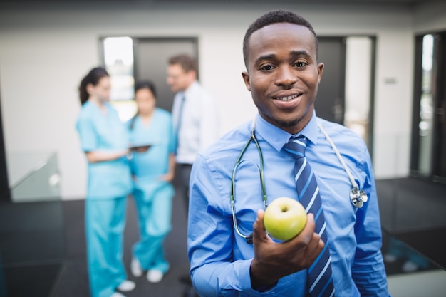 Foto grátis médico segurando maçã verde no corredor do hospital