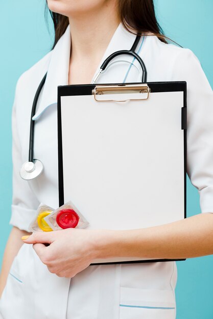 Médico segurando preservativos e uma prancheta vazia