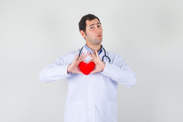 Médico segurando um coração vermelho no jaleco branco