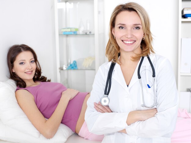 Médico sorridente e bela jovem grávida no hospital - dentro de casa