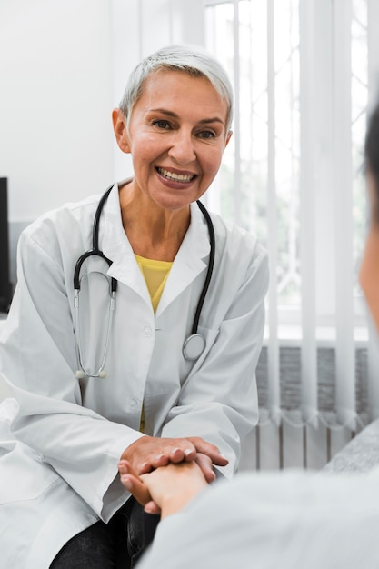 Foto grátis médico sorridente segurando a mão de um paciente