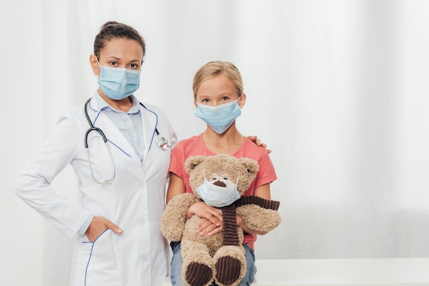 Foto grátis médico tiro médio e criança com urso