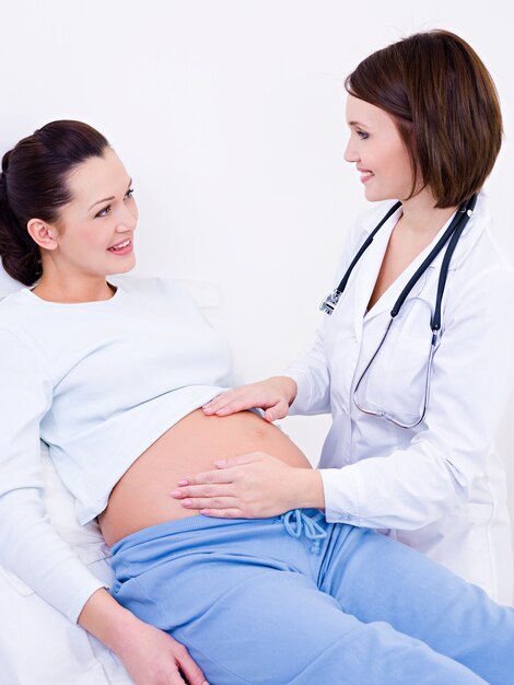 Médico toca a barriga de uma mulher grávida