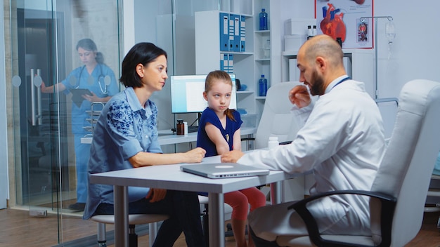 Médico trabalhando em exames diagnósticos para saúde infantil, falando e escrevendo. Especialista em medicina na prestação de serviços de saúde consulta exame diagnóstico tratamento em armário de hospital