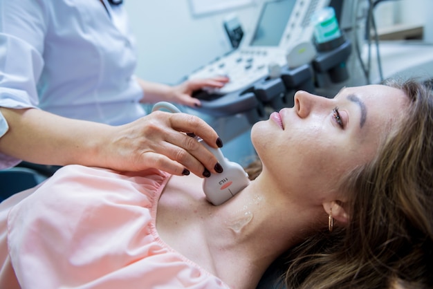 Médico usando máquina de ultrassom para examinar a tireoide de uma mulher
