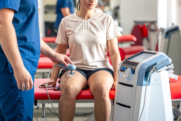 Médico usando máquina para tratar as articulações do joelho de um paciente