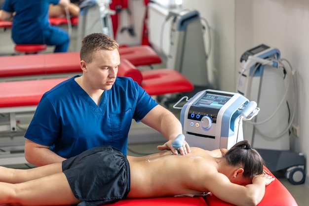 Médico usando uma máquina para tratar as costas de um paciente