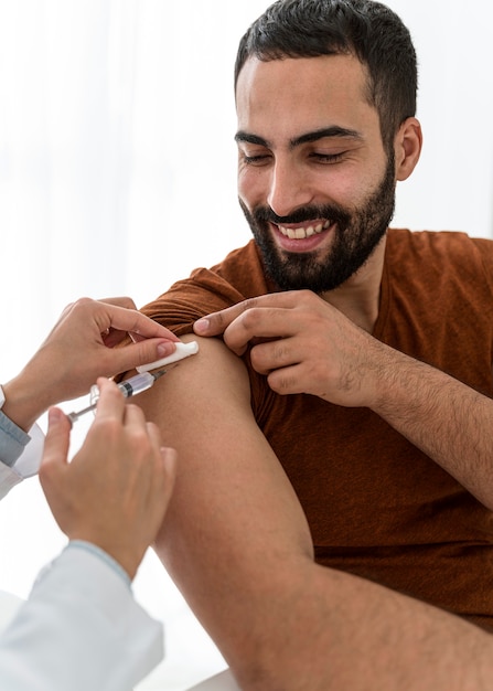 Médico vacinando um belo homem barbudo