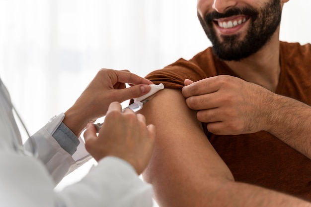 Médico vacinando um homem sorridente
