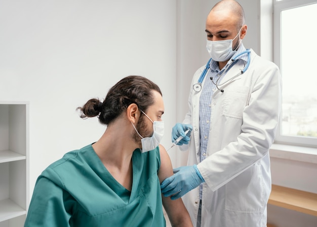 Médico vacinando um paciente na clínica